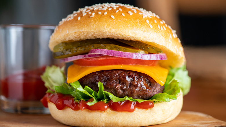 A juicy-looking homemade burger piled with fresh toppings and a toasted bun.