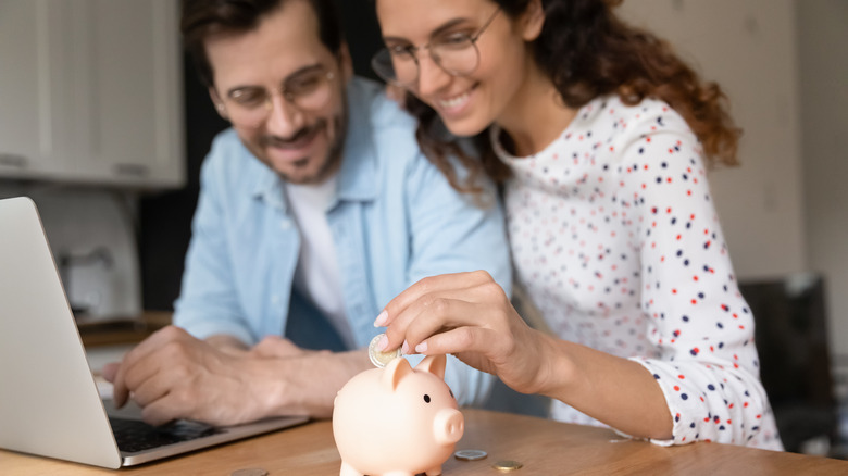 A smiling couple saving coins