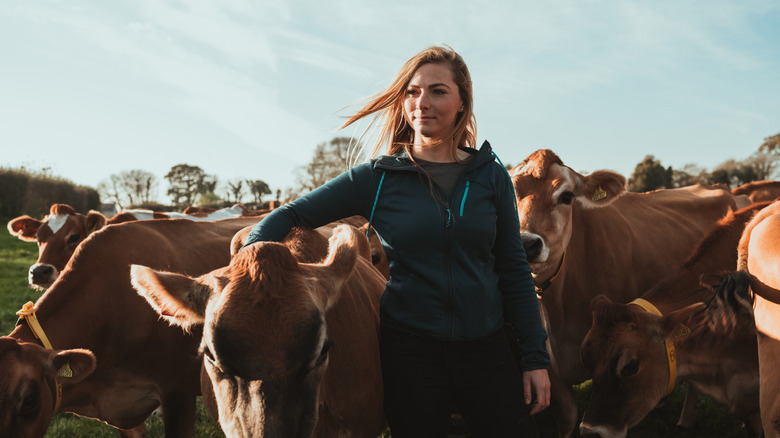 A woman standing in a field with cows