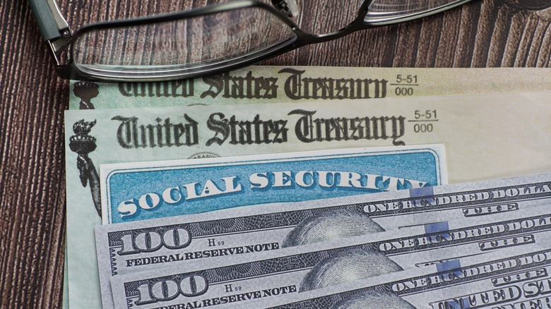 Social Security checks under Social Security card and hundred dollar bills