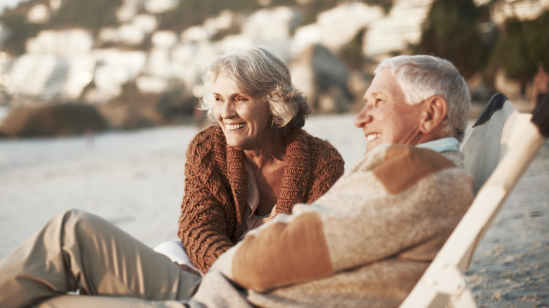 A smiling senior man and woman sitting on a beach