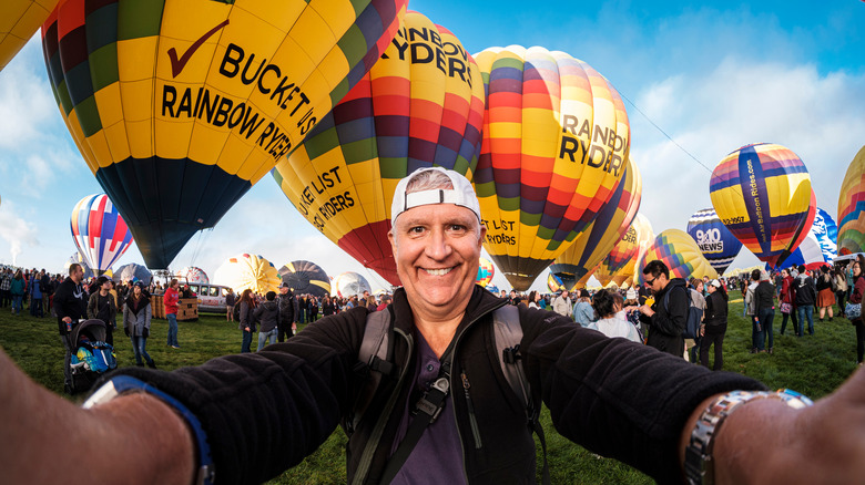 A smiling senior man with a bunch of hot air balloons behind him