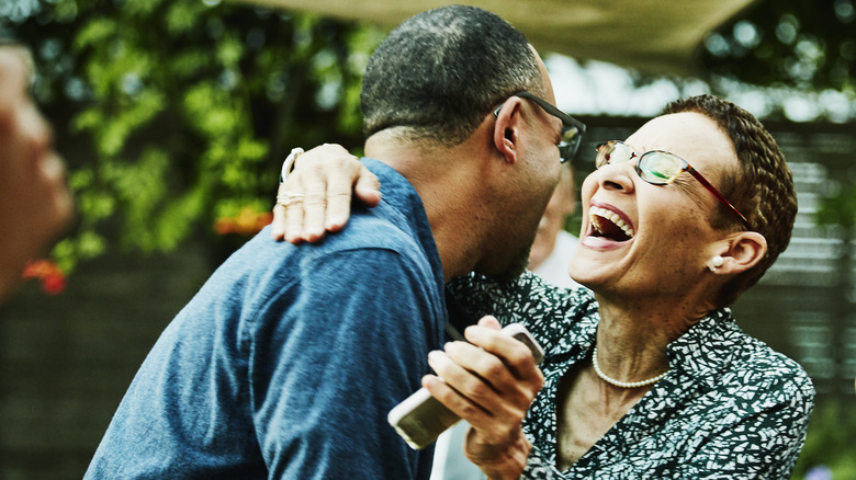 A senior couple laughing while dancing together in a backyard