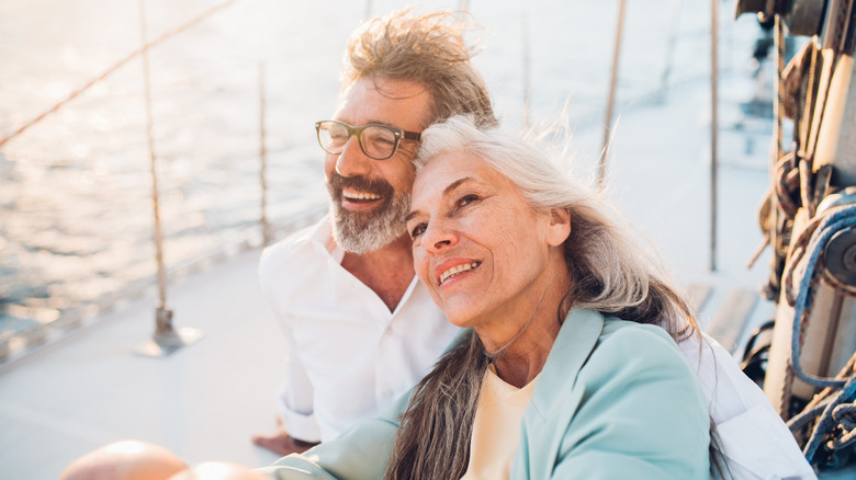 A retired couple smiling on a boat while embracing