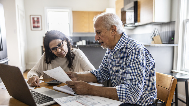 Senior couple paying bills at kitchen table