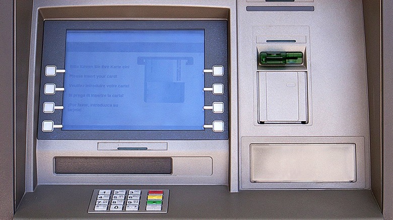 Medium shot of an unmarked ATM with European languages on menu screen