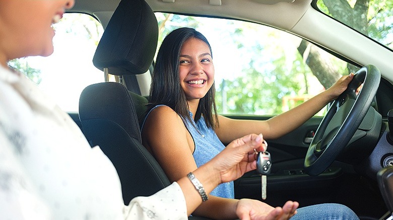 Teen driver holding out hand to receive key from parent