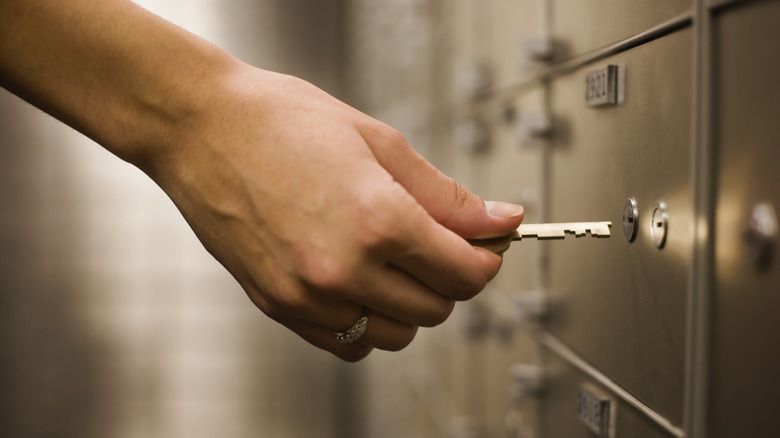 Person opening safe deposit box with key