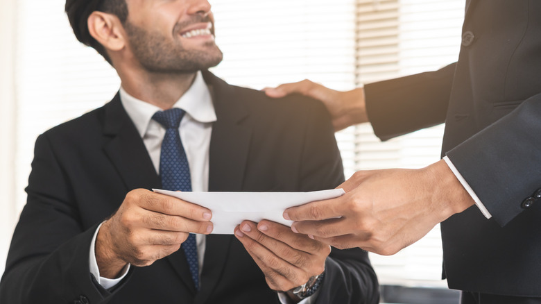 A manager man giving financial reward in an envelope to an employee