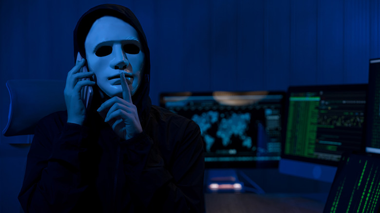 A person on a cell phone wearing a hoodie and a mask.