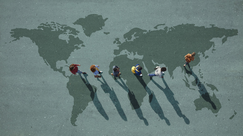 students walking across map of world, view from above