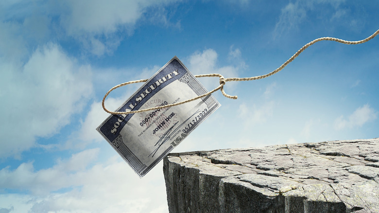 A lassoed social security card on the edge of a cliff, in front of a blue sky.