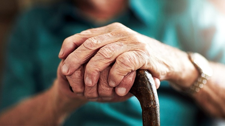 Senior citizen's hands on cane