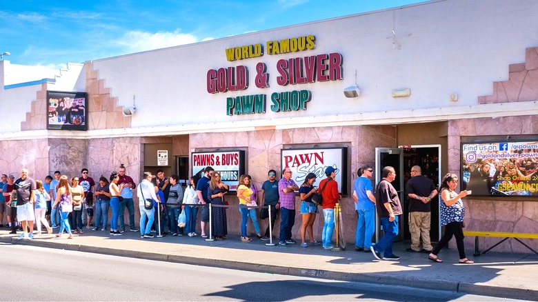 A line of people standing outside the Gold & Silver Pawn Shop