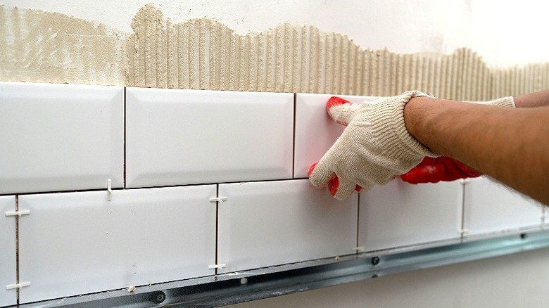 Person installing white subway tiles