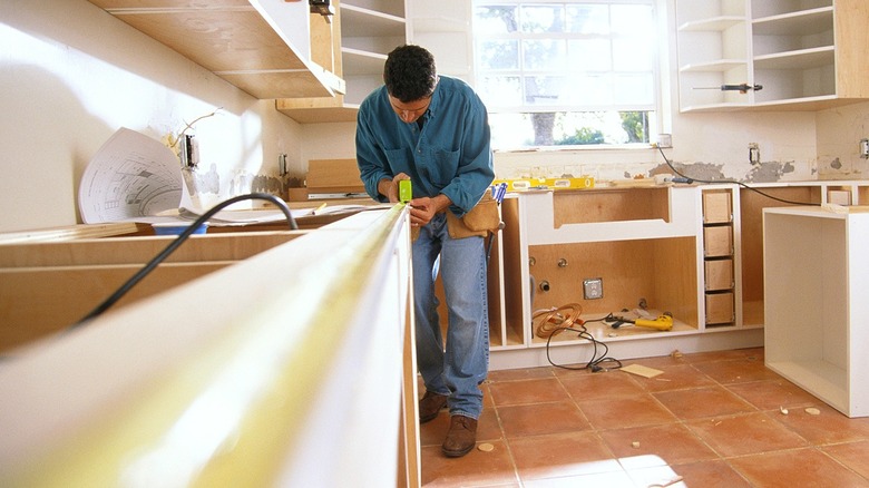 Person taking a measurement in a kitchen going through a remodel