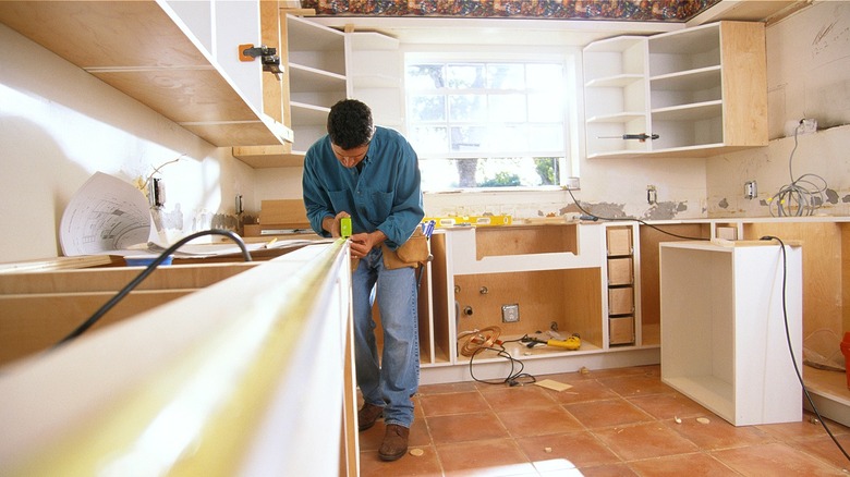 Person taking a measurement in a kitchen going through a remodel