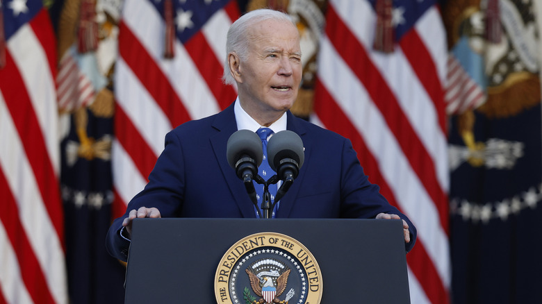 Joe Biden addresses crowd from a podium in front of many American flags.