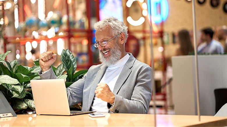 Person celebrating, reading from laptop