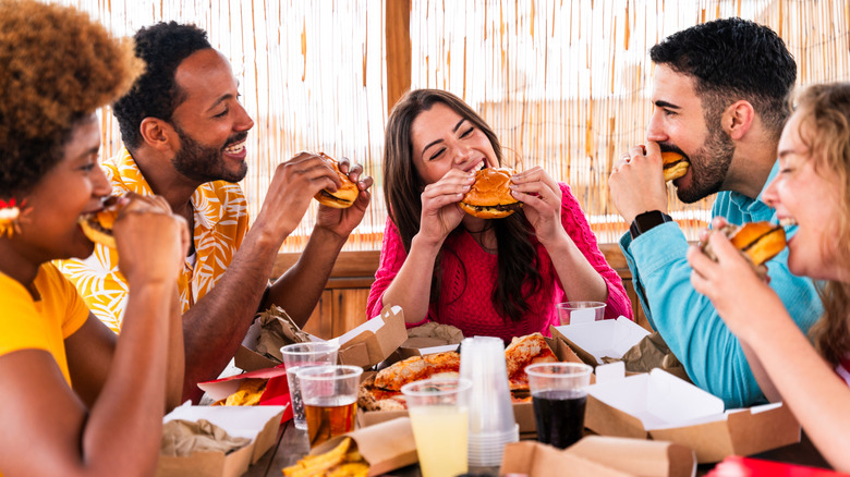 A group of people eating burgers at a restaurant