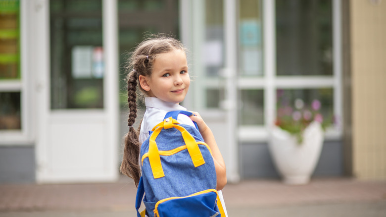 a child holding backpack at school