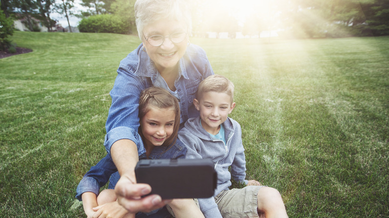 A senior woman taking a selfie with two children