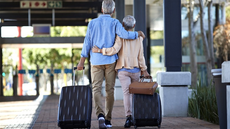 Senior couple walking with suitcases