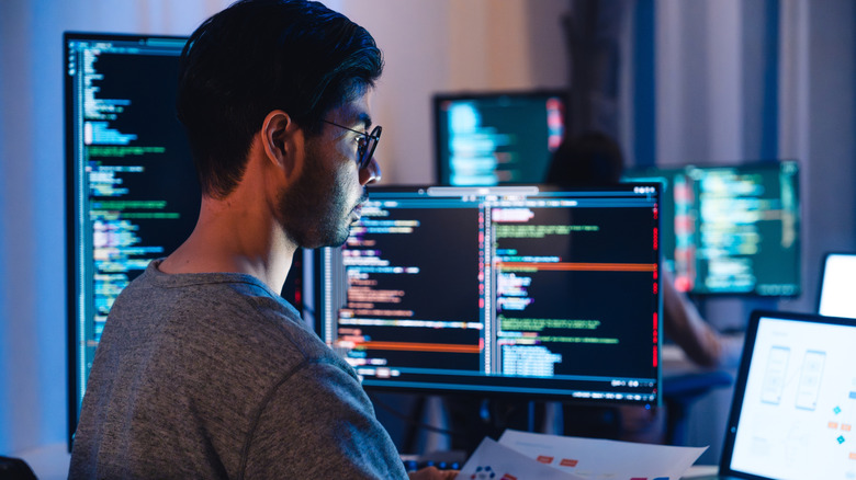 A software developer working on multiple screens