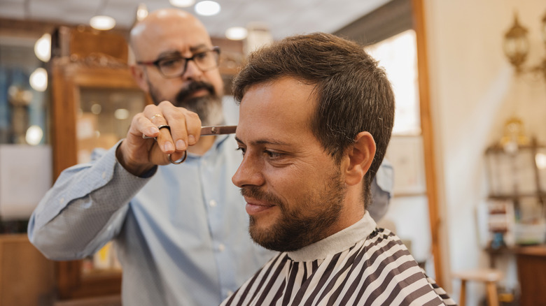 Barber cuts hair with scissors and comb in a barber shop