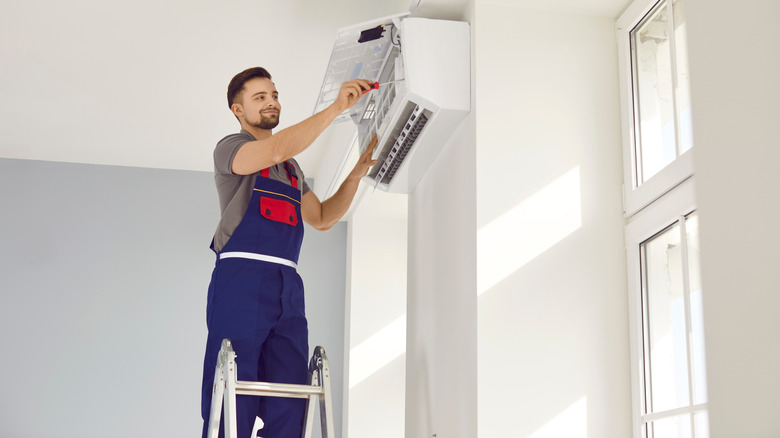 Male worker fixing air conditioning at home.