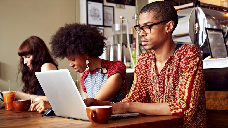 Three people sitting at coffee shop table working