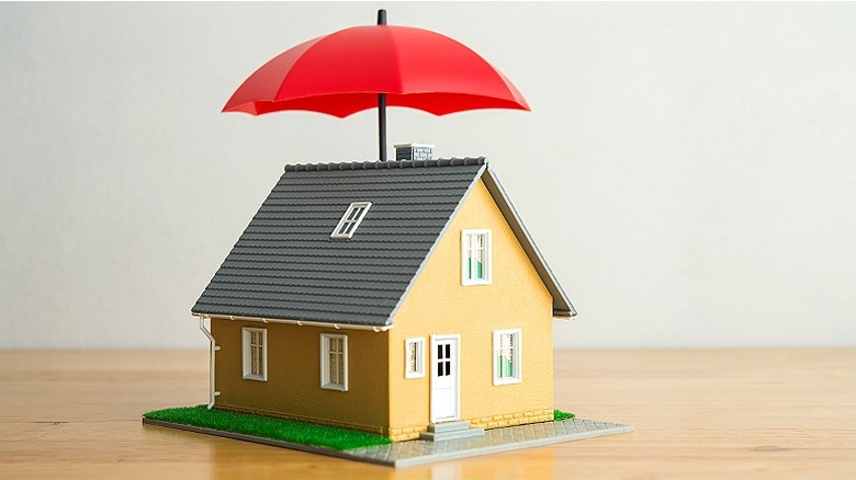 Miniature home model with umbrella on wooden table