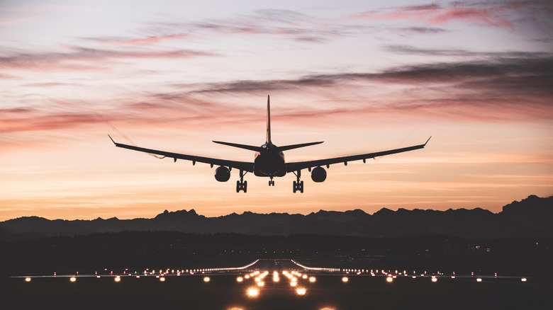 An airplane moments from touching down on the runway at sunrise.