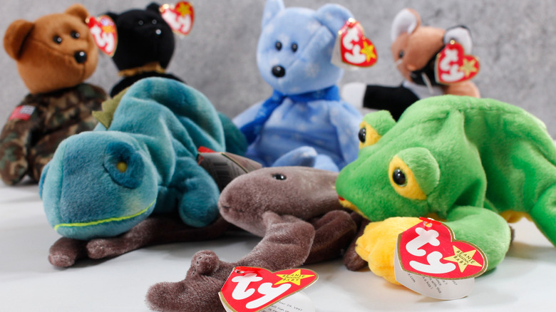 A collection of vintage Beanie Babies, complete with heart-shaped Ty swing tags, against a gray background.