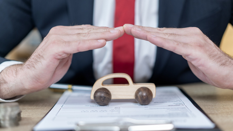 car figure under an insurance broker's hands