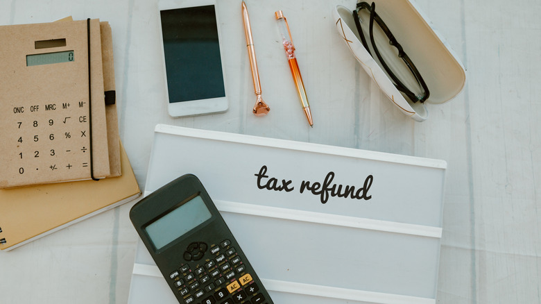 Tax refund next to calculators, phone, pens, and glasses