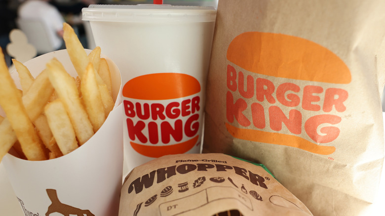 A Burger King Whopper meal, complete with fries, drink, and paper bag, fill the frame.