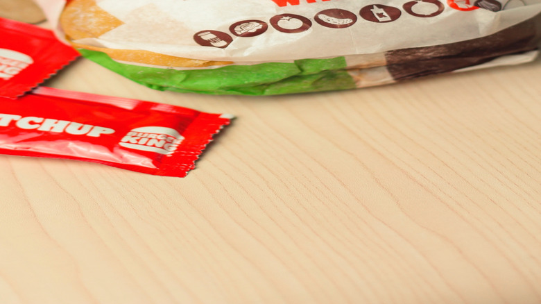 A pair of wrapped Whopper Juniors with cheese on a laminate table.