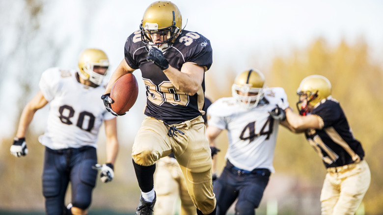 Football players chasing after a running back on a football field