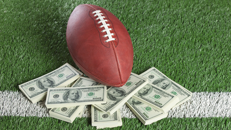 A football resting on stacks of U.S. currency