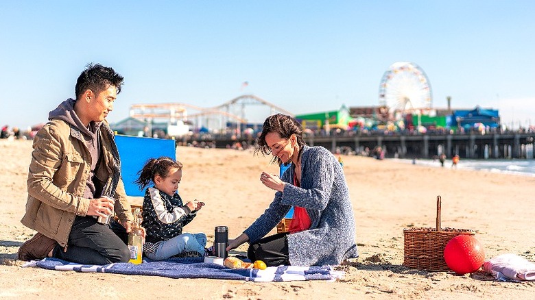 Family of three picnic on the beach with Santa Monica Pier in the background