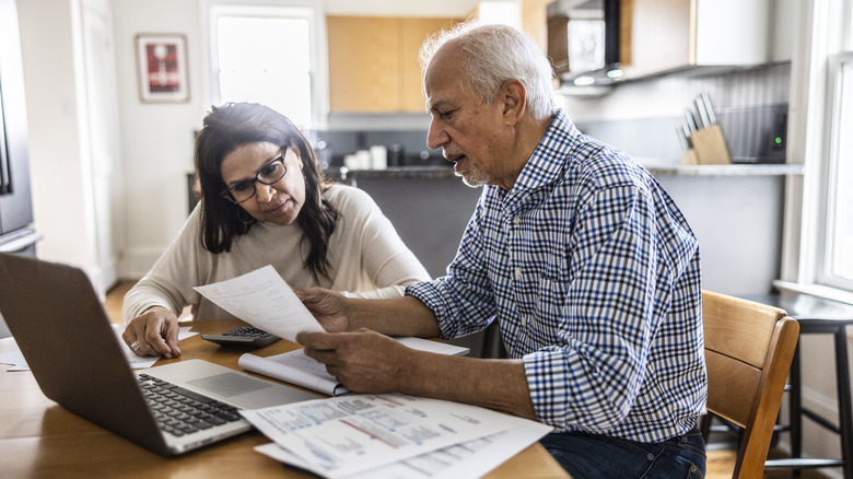 Senior couple paying bills at kitchen table