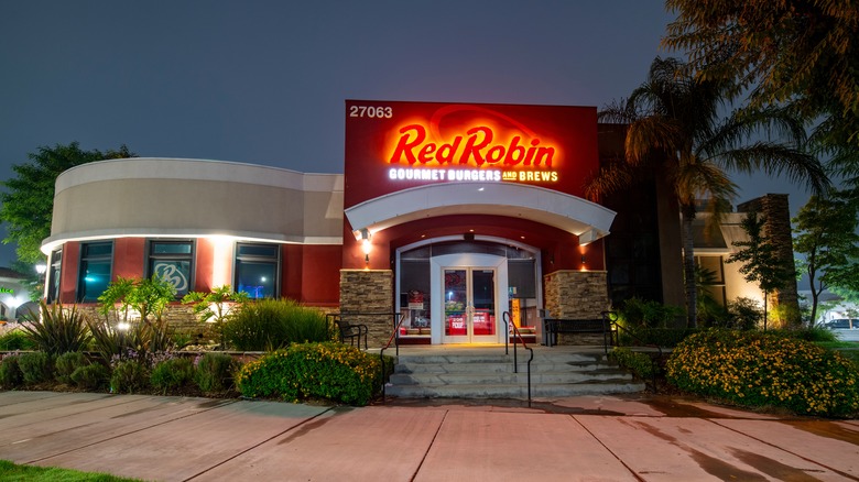 A Santa Clarita Red Robin restaurant at night, aglow under a palm tree.