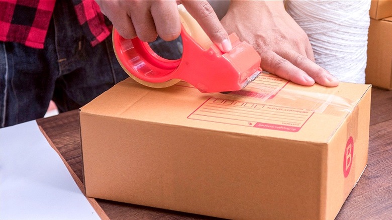 Person taping box to ship