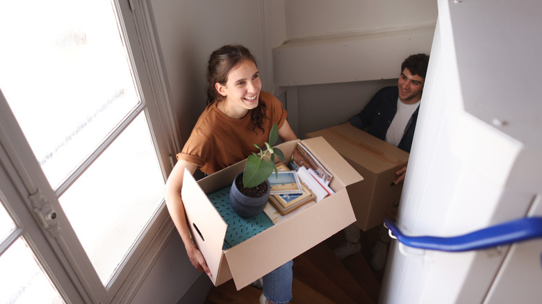 A young couple moving boxes up stairs