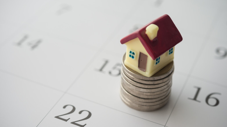 A miniature house on a stack of coins