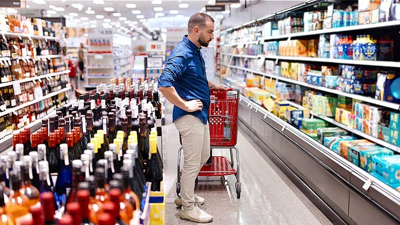 Man with shopping cart looking at empty spot on grocery shelf