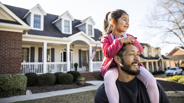 Man and little girl in front of a house.