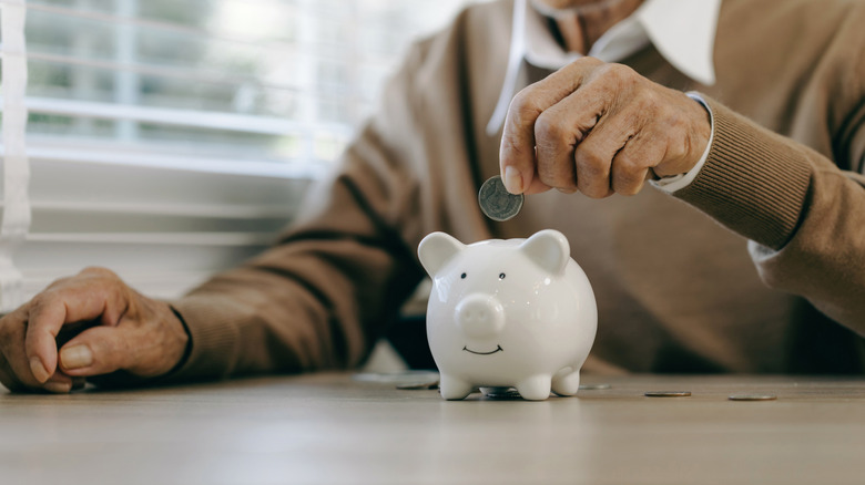 Man adding money to a piggy bank.