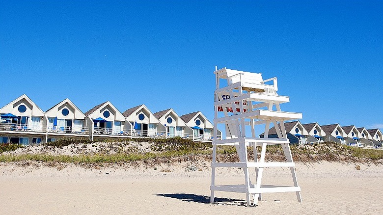 A white lifeguard chair on a Montauk beach lined with beachhouses.